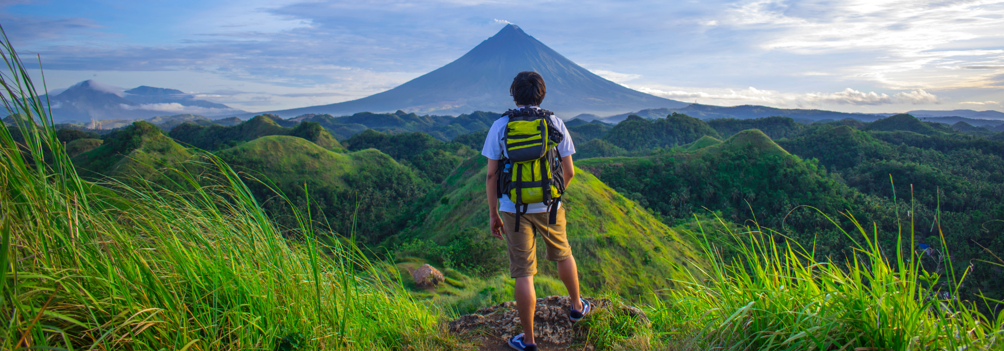 photo d'un homme de dos au milieu de la nature face à une montagne