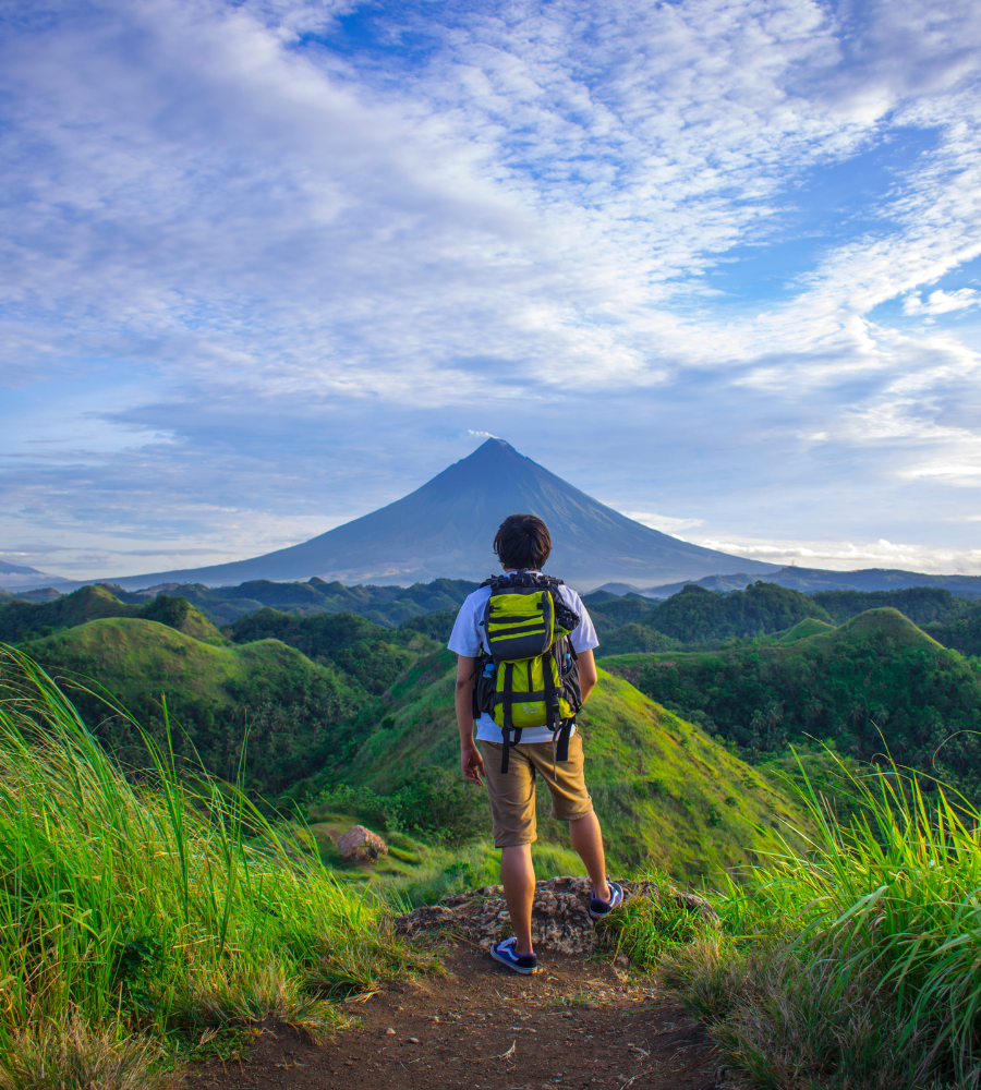 photo d'un homme de dos au milieu de la nature face à une montagne